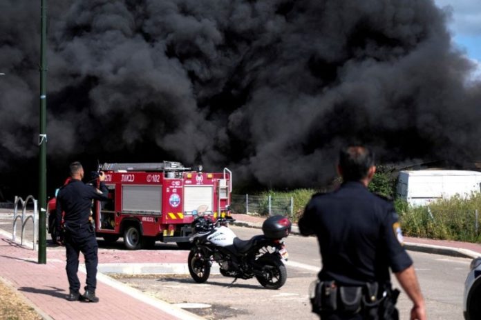 Policías israelíes junto al humo de un incendio tras el lanzamiento de cohetes desde Líbano a Israel en Bezet, norte de Israel.