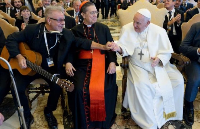 León Gieco saluda al Papa, entre ambos, el cardenal español Miguel Ayuso.